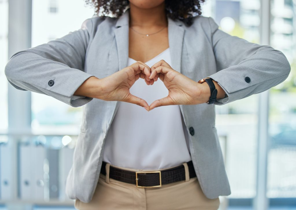 Closeup of woman in business attire holding her hands in the shape of a heart