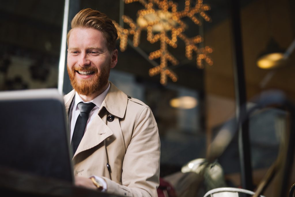 Smiling businessman works outside a cafe in winter
